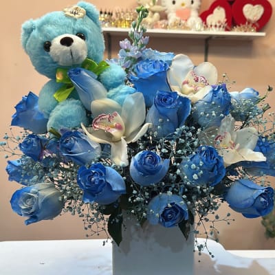 Blue rose bouquet with white orchids and a blue teddy bear in a white vase