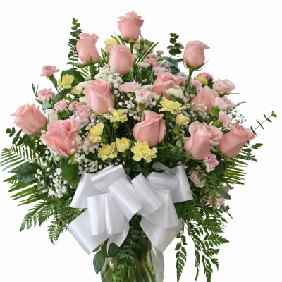 Pink roses and mixed flowers in a glass vase with a white bow