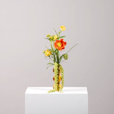 Small orange and yellow flower arrangement in an amber vase