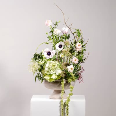 Tall floral arrangement in a pedestal bowl with pale pink and white blooms