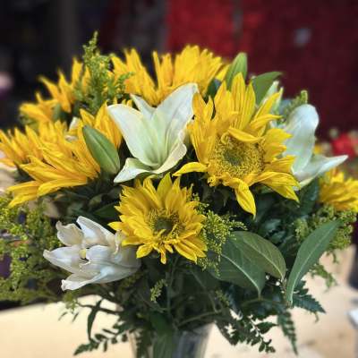 Yellow sunflowers and white lilies in a glass vase