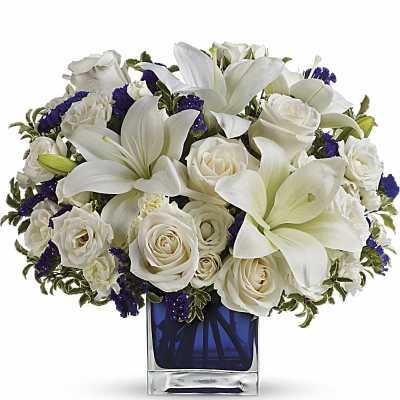 White lilies and roses arranged in a blue glass vase