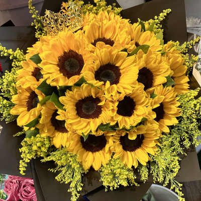 Bouquet of yellow sunflowers with dark wrapping and a decorative crown