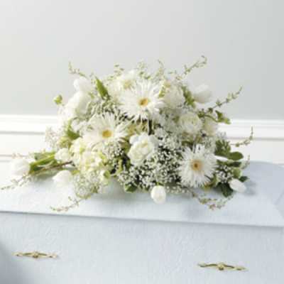 White floral arrangement on a casket with daisies and roses