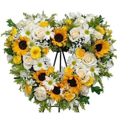 Heart-shaped floral wreath with sunflowers, white roses, and daisies on a stand