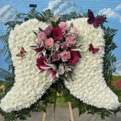 Large white floral funeral spray with pink and purple flowers and butterflies