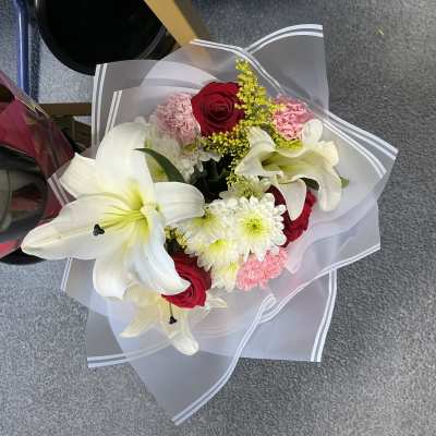Bouquet of white lilies, red roses, pink carnations, and white daisies
