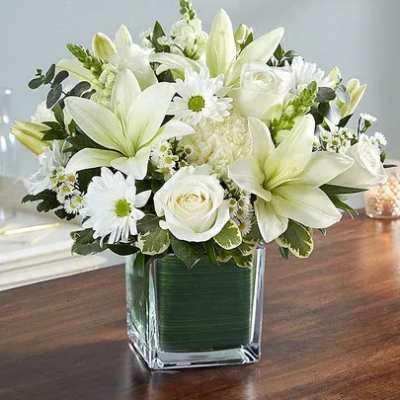 White lilies and roses arranged in a square glass vase
