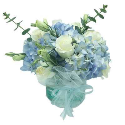 Blue and white bouquet in a teal vase with a sheer ribbon
