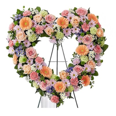 Heart-shaped floral wreath with pink, peach, and lavender blooms on an easel