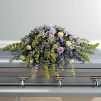 Pastel floral casket spray with purple, yellow, and white blooms