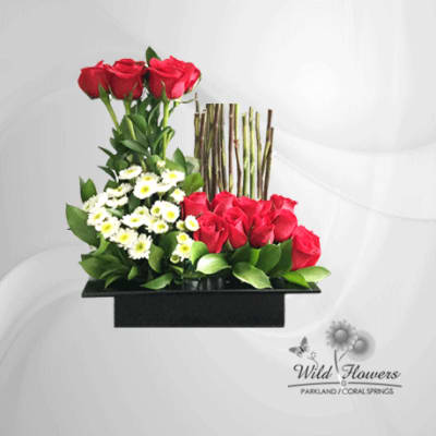 Red roses and white daisies arranged in a black rectangular vase