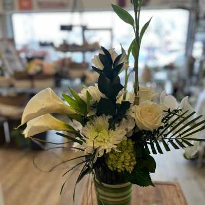 White calla lilies and roses arranged in a green striped vase