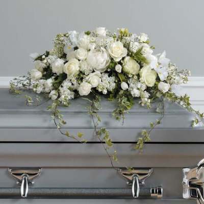 White floral casket spray with trailing greenery