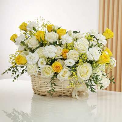 Yellow and white roses arranged in a wicker basket