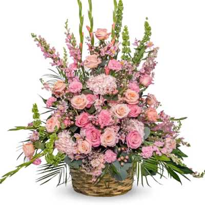 Pink and peach floral arrangement in a woven basket