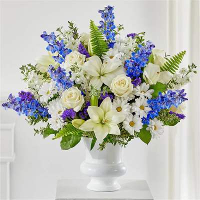 White and blue floral arrangement in a white pedestal vase