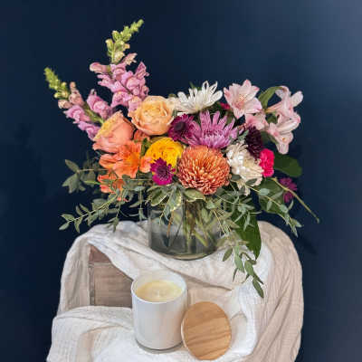 Mixed bouquet in a glass vase with a candle in front