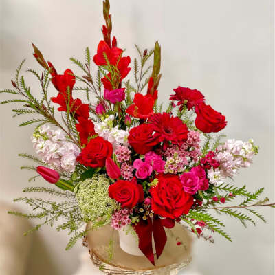 Red and pink floral arrangement in a white vase