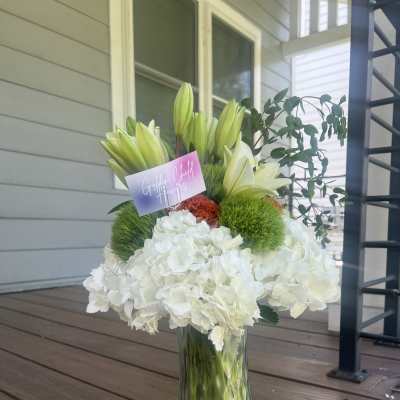White hydrangeas and lilies arranged in a glass vase