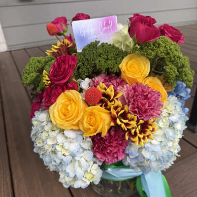 Colorful bouquet of roses, hydrangeas, and carnations in a glass vase
