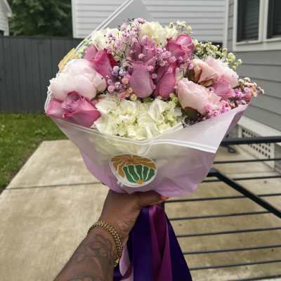 Pink and white bouquet of roses, hydrangeas, and baby's breath wrapped in pastel paper