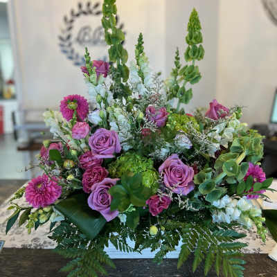 Lavender roses and pink blooms in a low rectangular arrangement