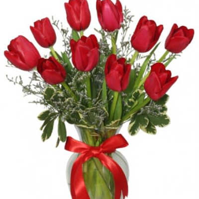 Red tulips arranged in a glass vase with a red ribbon