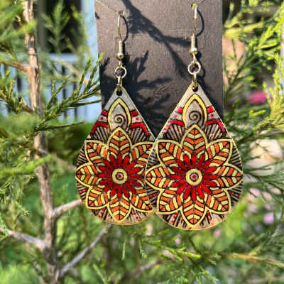 Pair of patterned teardrop earrings hanging outdoors