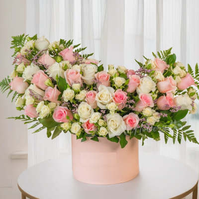 Pink and white roses arranged in a blush round box