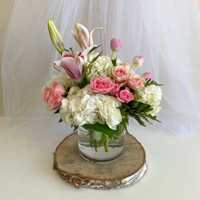 Pink roses and white hydrangeas in a glass vase with lilies and tulips