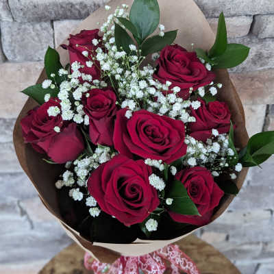 Bouquet of red roses with white baby's breath in brown paper