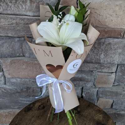 White lily bouquet wrapped in beige paper with a white ribbon