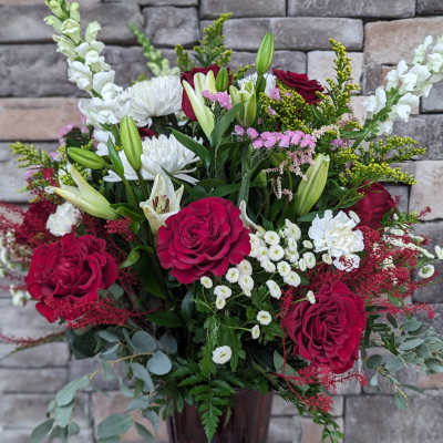 Bouquet of red roses, white lilies, and white snapdragons in a tall vase
