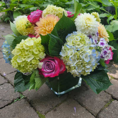 Mixed bouquet of hydrangeas, roses, and dahlias in a glass vase