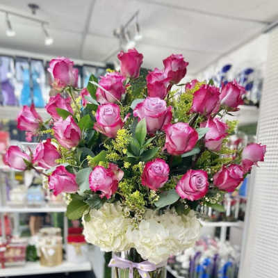 Tall vase arrangement of hot pink roses and white hydrangeas tied with a ribbon