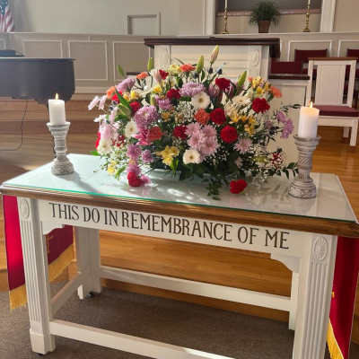 Large mixed flower arrangement on a church altar with two candles