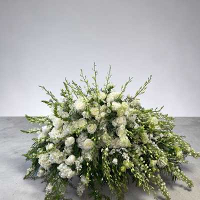 Low, elongated arrangement of white flowers with arching green buds in an all-around spray shape