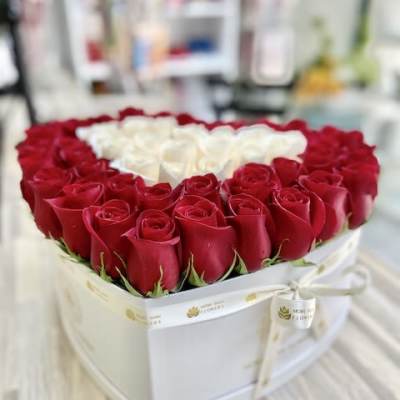 Heart-shaped white box filled with red roses around a cluster of white roses in the center