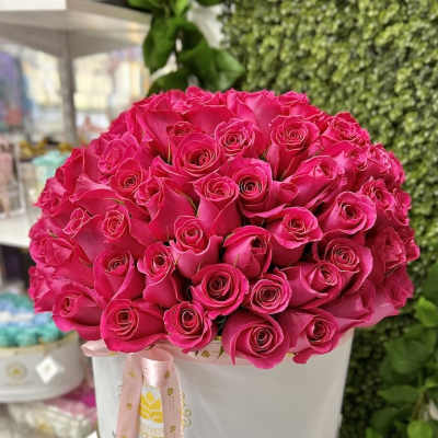 Large arrangement of hot pink roses in a white hat box with a pink ribbon