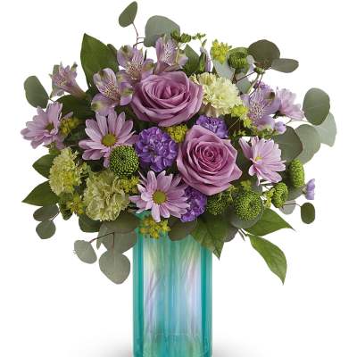 Lavender roses and mixed purple flowers in a turquoise glass vase