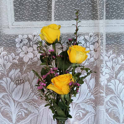 Yellow roses in a glass vase with a small white teddy bear
