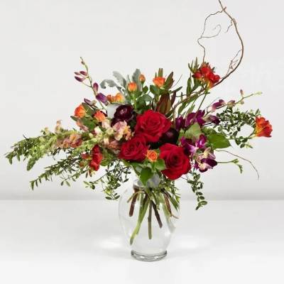 Mixed bouquet of red roses and purple orchids in a clear glass vase