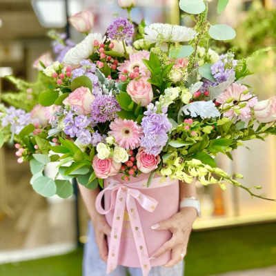Large pastel flower arrangement with pink roses, gerberas, and lavender blooms in a pink hatbox with ribbon.
