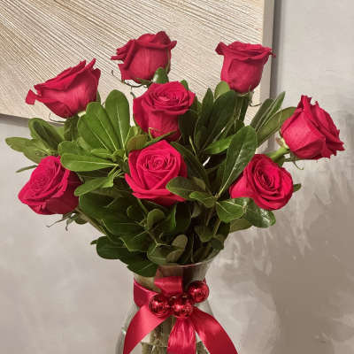 Bouquet of red roses in a glass vase with a pink ribbon