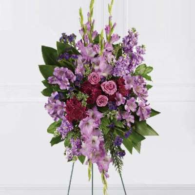 Standing spray of purple flowers with pink roses on a metal easel