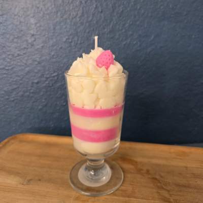 Layered pink and white candle in a glass goblet with a strawberry topper