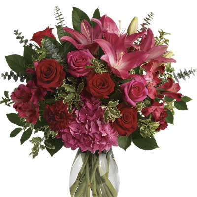 Bouquet of pink lilies and red roses in a clear glass vase