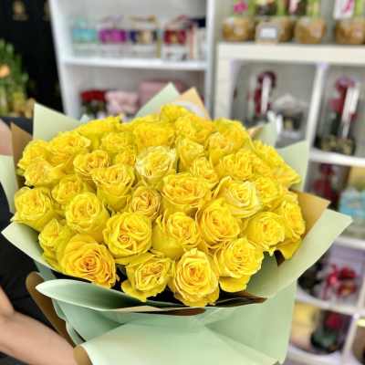Large bouquet of bright yellow roses wrapped in pale mint paper