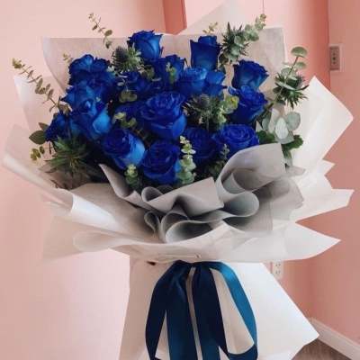 Bouquet of blue roses wrapped in white paper with a blue ribbon